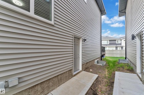 Side exterior access door with concrete walkway, gray vinyl siding, and white window trim - 1827 22 Street Nw, Edmonton, AB - Outdoor With Exterior