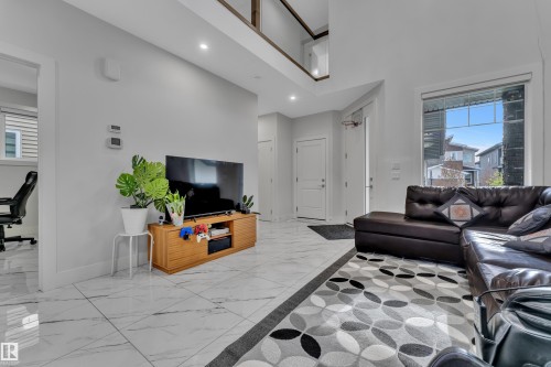 Bright interior space featuring white marble-look tile flooring, high ceilings, recessed lighting, and a large window - 1827 22 Street Nw, Edmonton, AB - Indoor Photo Showing Living Room