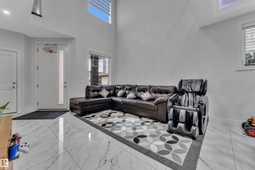 Spacious room featuring high ceilings, white walls, and large format white marble-look tile flooring - 1827 22 Street Nw, Edmonton, AB - Indoor Photo Showing Living Room