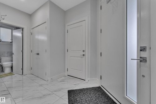 Foyer featuring white paneled doors, modern lever hardware, and large format marble-look tile flooring - 1827 22 Street Nw, Edmonton, AB - Indoor Photo Showing Other Room