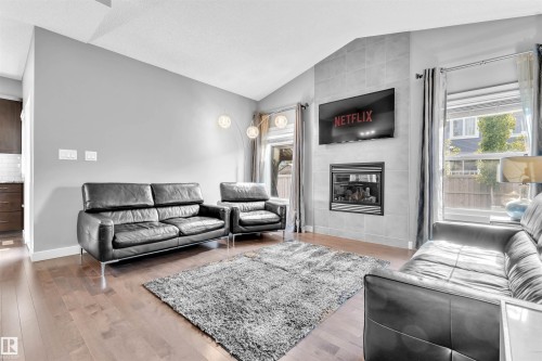The living area features hardwood floors and a fireplace with a tiled surround - 8108 217 Street, Edmonton, AB - Indoor Photo Showing Living Room With Fireplace