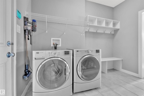 The property features a laundry area with a washer and dryer, a built-in bench, and wall-mounted shelving with hooks - 8108 217 Street, Edmonton, AB - Indoor Photo Showing Laundry Room
