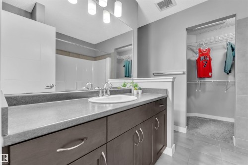 The bathroom features a vanity with a white sink, chrome faucet, and dark cabinetry - 8108 217 Street, Edmonton, AB - Indoor Photo Showing Bathroom