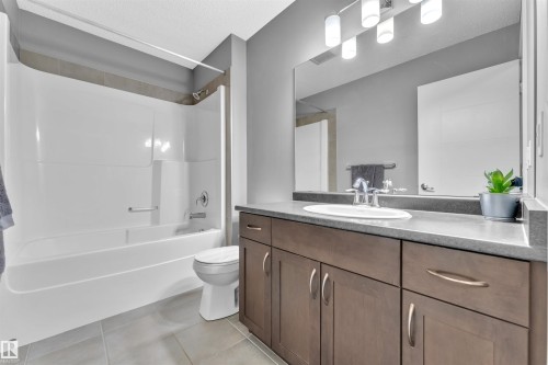 Bathroom featuring a vanity with a countertop sink, a large mirror, and a bathtub with an integrated shower - 8108 217 Street, Edmonton, AB - Indoor Photo Showing Bathroom