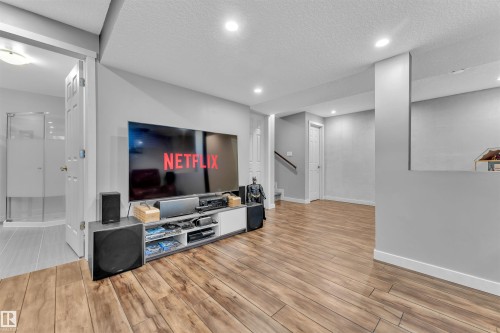 Living area featuring wood-look flooring, recessed lighting, and access to a bathroom with a glass-enclosed shower - 8108 217 Street, Edmonton, AB - Indoor