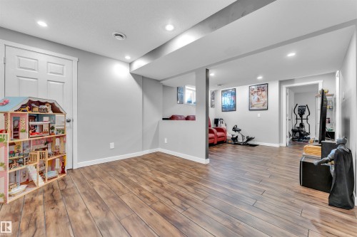 Spacious room featuring wood-look flooring, light gray walls, and recessed lighting - 8108 217 Street, Edmonton, AB - Indoor
