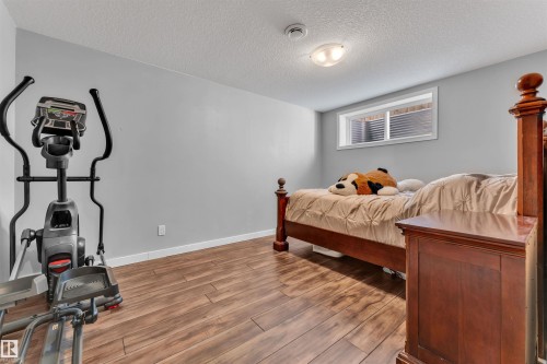 This room features gray walls, wood-look flooring, and a window with blinds - 8108 217 Street, Edmonton, AB - Indoor Photo Showing Gym Room