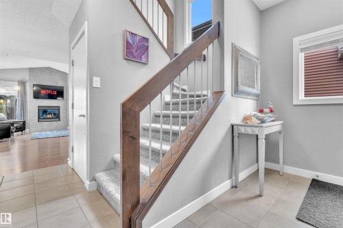 The property features a staircase with carpeted treads and a wooden handrail with metal balusters - 8108 217 Street, Edmonton, AB - Indoor Photo Showing Other Room