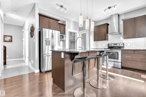 Well-appointed kitchen featuring hardwood floors, dark wood cabinetry, granite countertops, and stainless steel appliances - 8108 217 Street, Edmonton, AB - Indoor Photo Showing Kitchen With Upgraded Kitchen