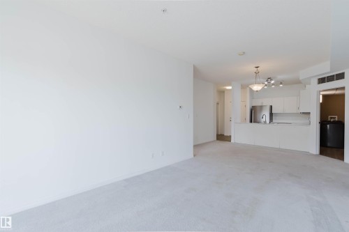 Open-concept living space featuring light-colored carpeting and a full kitchen - 308 4316 139 Avenue, Edmonton, AB 