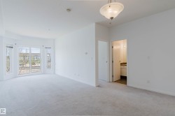 Spacious room featuring light-toned carpet flooring, a large bay window with multiple panes, and a contemporary ceiling light fixture - 