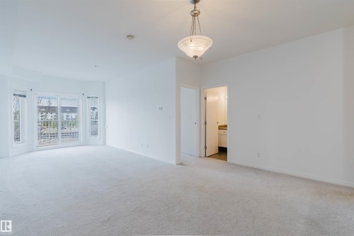 Spacious interior room featuring light-toned carpet flooring and a neutral color palette - 308 4316 139 Avenue, Edmonton, AB 