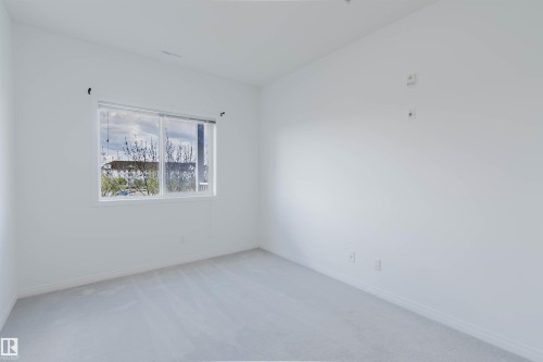 Bright interior space featuring a large window, neutral paint, and light-toned carpeting - 308 4316 139 Avenue, Edmonton, AB 