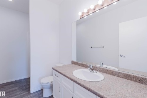 Bathroom vanity with an integrated sink, a speckled countertop, and a large mirror - 308 4316 139 Avenue, Edmonton, AB 