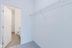 Carpeted closet space featuring a built-in wire shelving system and direct access to a bathroom with wood-finish flooring and a vanity - 