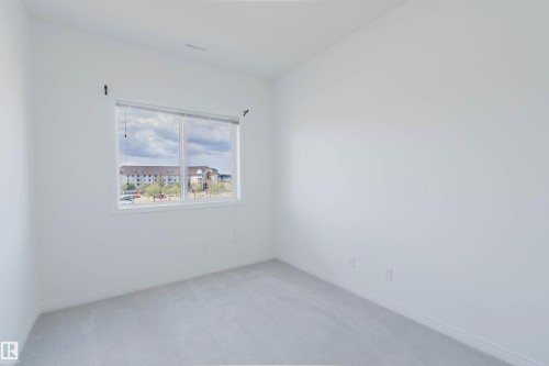 Bright room featuring a large window, neutral carpeting, and crisp white walls - 308 4316 139 Avenue, Edmonton, AB 