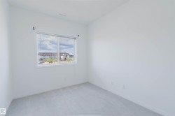Bright room featuring a large window, neutral carpeting, and crisp white walls - 