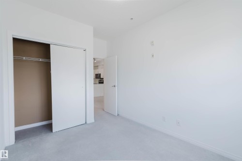 Bedroom featuring white walls, light gray carpet, and a bi-fold closet with shelving and a hanging rod - 308 4316 139 Avenue, Edmonton, AB 
