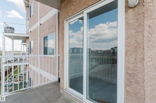Patio with white metal railing and concrete flooring, featuring a large sliding glass door - 308 4316 139 Avenue, Edmonton, AB 