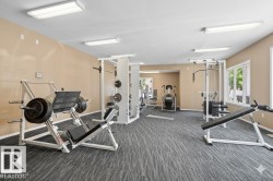 Fitness room featuring patterned grey carpeting, light beige walls, and white ceiling panels - 