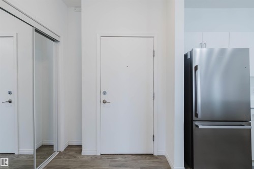 Entryway featuring wood-finish flooring, white walls, and a mirrored closet door - 308 4316 139 Avenue, Edmonton, AB 
