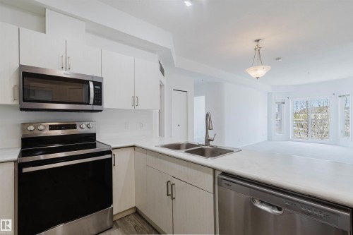 Modern kitchen with light cabinetry, stainless steel appliances, and a double basin sink with a high-arc faucet - 308 4316 139 Avenue, Edmonton, AB 