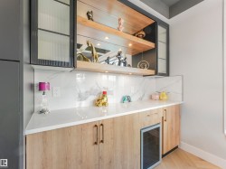 Built-in bar area featuring light wood-finish cabinetry, white countertop, and a matching backsplash - 