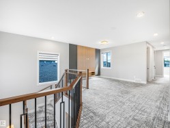 Upper-level landing featuring a contemporary wood and metal railing, recessed lighting, and a textured carpet - 