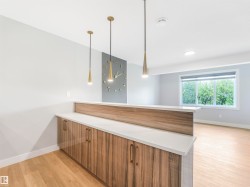 Modern bar area featuring wood-grain cabinetry, a light-toned countertop, and three contemporary pendant lights - 