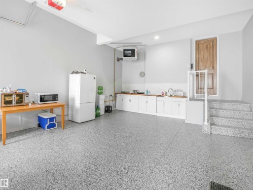 Spacious utility area featuring durable epoxy flooring, extensive white cabinetry with wood-finish countertops, and a built-in sink - 15 Elwyck Gate, Spruce Grove, AB - Indoor