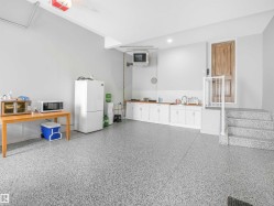 Spacious utility area featuring durable epoxy flooring, extensive white cabinetry with wood-finish countertops, and a built-in sink - 