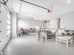 Spacious garage with an epoxy coated floor, a paneled overhead door with windows, recessed lighting, and a built-in kitchenette area - 