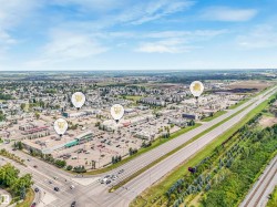 Aerial view showcasing a commercial district with multiple retail establishments, extensive parking areas, and convenient access to a multi-lane highway - 