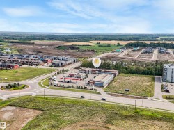 Aerial perspective showcasing a commercial building with an expansive paved parking lot, surrounded by developed residential areas and undeveloped land - 