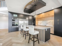 Contemporary kitchen featuring a large central island with a waterfall countertop, integrated sink, and modern pendant lighting - 