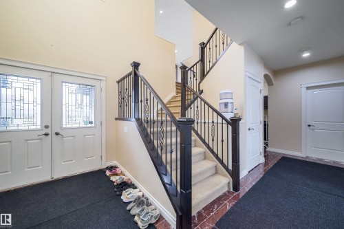 Grand foyer featuring a dual staircase with wrought iron balusters and dark wood newel posts - 1508 Cunningham Cape Cape, Edmonton, AB - Indoor Photo Showing Other Room