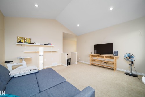 Carpeted loft area featuring a vaulted ceiling with recessed lighting, a built-in shelving unit, and painted beige walls - 1508 Cunningham Cape Cape, Edmonton, AB - Indoor