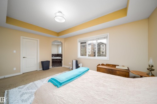 Spacious room featuring a tray ceiling with recessed lighting, carpet flooring, and a large window - 1508 Cunningham Cape Cape, Edmonton, AB - Indoor Photo Showing Bedroom