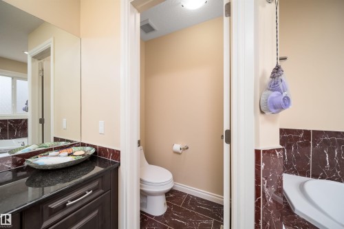 Bathroom with dark wood-finish vanity, black countertop, full-width mirror, and dark marble-look tile flooring - 1508 Cunningham Cape Cape, Edmonton, AB - Indoor Photo Showing Bathroom
