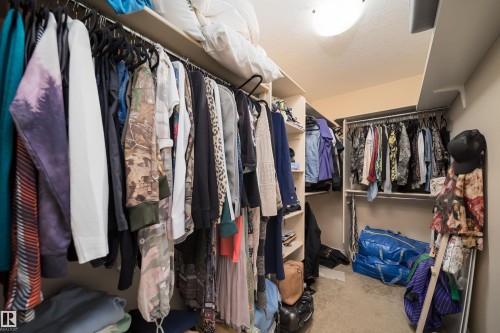 Walk-in closet featuring extensive built-in shelving, multiple hanging rods, and recessed ceiling lighting - 1508 Cunningham Cape Cape, Edmonton, AB - Indoor With Storage