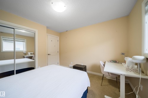 Carpeted room featuring a double-pane window with blinds, a mirrored sliding closet door, a solid panel interior door, and a flush mount ceiling light - 1508 Cunningham Cape Cape, Edmonton, AB - Indoor Photo Showing Bedroom