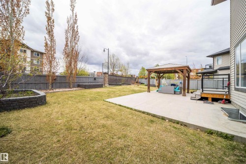 Spacious backyard featuring a concrete patio, wooden gazebo, expansive lawn area, and a tiered deck with glass railings - 1508 Cunningham Cape Cape, Edmonton, AB - Outdoor