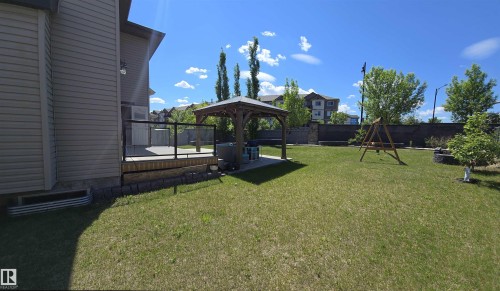 Expansive backyard featuring a manicured lawn, a wooden deck with glass panel railing, and a permanent gazebo structure - 1508 Cunningham Cape Cape, Edmonton, AB 