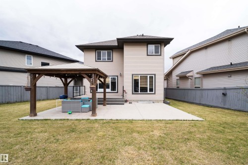 Expansive backyard featuring a wood-finish pergola with string lighting, a concrete patio area, and a stepped deck with glass railing - 1508 Cunningham Cape Cape, Edmonton, AB - Outdoor
