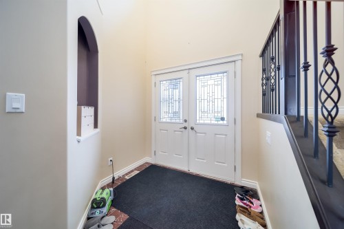 Double entry doors with leaded glass inserts, framed by a decorative arched wall niche - 1508 Cunningham Cape Cape, Edmonton, AB - Indoor Photo Showing Other Room