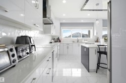 Modern kitchen with white shaker-style cabinetry, a built-in cooktop, and a matching range hood - 