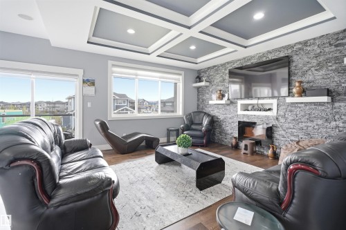 Living area featuring a coffered ceiling with recessed lighting, a stone accent wall, and wood-finish flooring - 3909 49 Ave, Beaumont, AB - Indoor Photo Showing Living Room With Fireplace