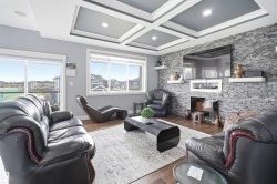 Living area featuring a coffered ceiling with recessed lighting, a stone accent wall, and wood-finish flooring - 