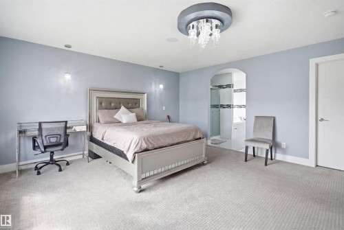 Spacious bedroom featuring light gray walls, recessed lighting, and a prominent crystal chandelier - 3909 49 Ave, Beaumont, AB - Indoor Photo Showing Bedroom