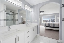 Contemporary bathroom featuring a double vanity with white cabinetry, light-toned countertops, and chrome fixtures - 
